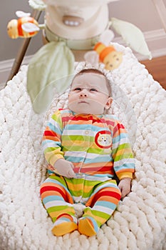 Cute adorable smiling white Caucasian baby boy girl lying in bouncer chair.