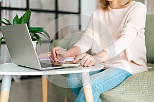 Cute adult senior mature woman in glasses checking text messages in her smartphone cell phone gadget, while doing online