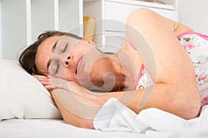 Cute adult woman in pygamas sleeping in bed in bedroom