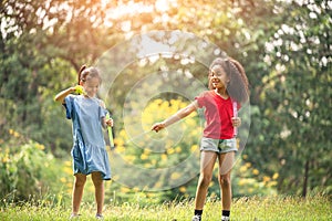 Cute african american and Asian little girl playing outdoor.  Friends happy playing with bubbles together