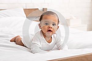 Cute African American Baby Infant In Longsleeve Lying In Bed