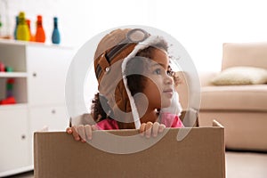 Cute African American child playing with cardboard box