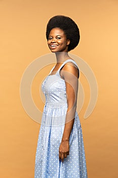 Cute African American female with beautiful afro hairstyle smiling,  beige studio background
