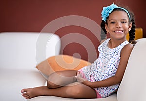 Cute african american girl sitting on a couch and smiling