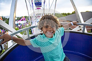 A cute African American little boy enjoying a Ferris Wheel ride at a local carnival