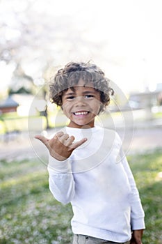 Cute African American little boy making a hang loose hand sign showing that he is happy and feeling good