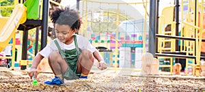 Cute African American little kid boy funny while playing on the playground in the daytime in the spring season. Outdoor activity.