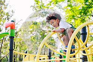 Cute African American little kid boy having fun while playing on the playground in the daytime in summer. Outdoor activity.