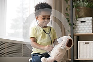 Cute african boy playing with toy as doctor holding stethoscope photo