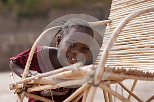 Cute African Girl Fooling Around With Her Traditional Cane Chair