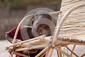Cute African Girl Fooling Around With Her Traditional Cane Chair photo