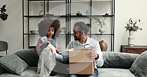 Cute African girl her dad unpack parcel box with kitchenware