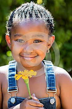 Cute african girl holding orange flower outdoors.