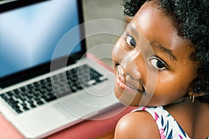 Cute african girl with laptop in background.