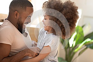 Cute african kid daughter laughing tickling black dad at home