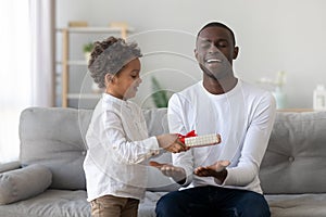 Cute african kid son giving gift to dad fathers day