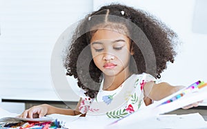 Cute African little girl drawing or sketching clothing design on paper at tailor room, cozy home as her career dream, smiling with