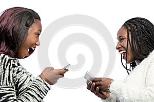 Cute african teen girls laughing with smart phones.