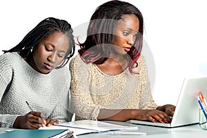 Cute african teen student working on laptop with friend.