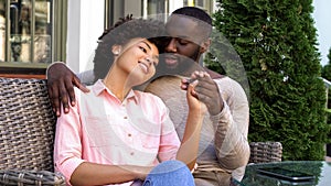 Cute afro-american couple relaxing in outdoor cafe, hugging and talking, love