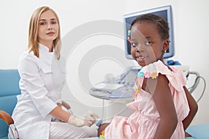 Cute afro girl sitting on bed during examines knee joints.