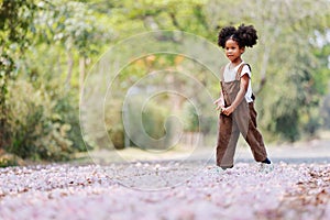 A cute Afro girls under flowering tree in park.