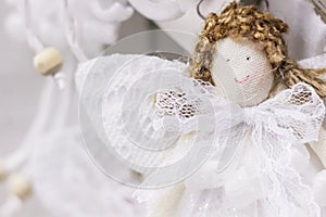 Cute angel textile handmade doll with curly hair, white lace wings and dress. Soft focus Christmas decorative background