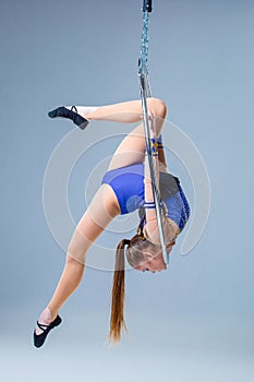 Cute artistic gymnast exercising with hanging hoop