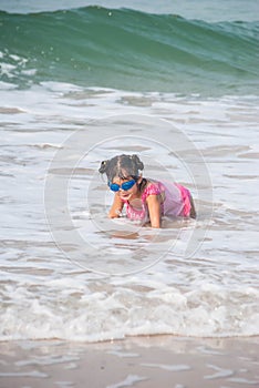 Cute asia girl having fun on the sunny tropical beach with wonderful waves around her.