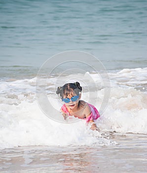 Cute asia girl having fun on the sunny tropical beach with wonderful waves around her.
