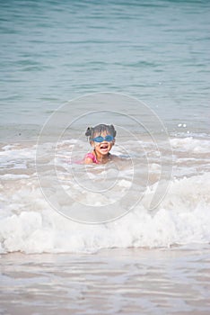 Cute asia girl having fun on the sunny tropical beach with wonderful waves around her.