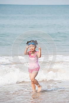 Cute asia girl having fun on the sunny tropical beach with wonderful waves around her.