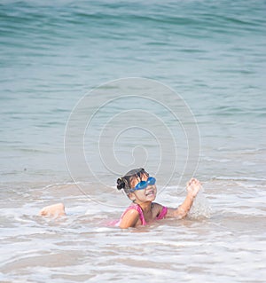 Cute asia girl having fun on the sunny tropical beach with wonderful waves around her.