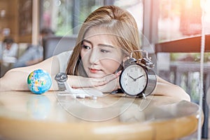 Cute asia girl looking to globe and alarm clock try to make dec