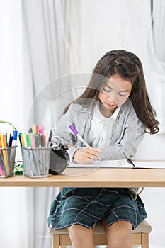 Cute Asia girl writing something in paper with colour pencils