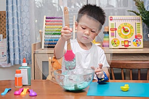 Cute  Asian 4 years old boy having fun making fluffy slime, Young kid having fun playing and being creative by science experiment