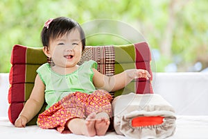 Cute asian baby girl in Thai traditon dress sitting with pillow