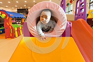 Cute Asian baby playing on the indoor playground