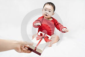 Cute asian baby in red bodysuit get gift box sitting on white blanket at home.Give Year present to child,kid,toddler.Concept
