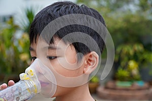 Cute Asian boy with asthma using inhaler and spacer,Inhaler, spacer and mask