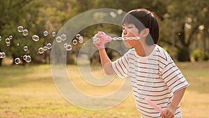 Cute Asian boy blowing soap bubbles at the park in natural afternoon sunlight enjoy the outdoor play date, carefree mind,concept