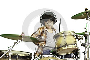 A cute Asian boy is enjoying playing the drums in a music classroom.