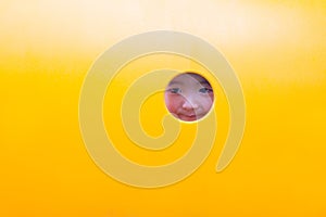 Cute Asian boy playing and smiling in yellow tunnel at the playground with sunlight yellow tube,