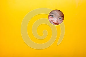 Cute Asian boy playing and smiling in yellow tunnel at the playground with sunlight yellow tube,