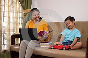 A cute Asian boy playing toy cars while accompanying his mother to work