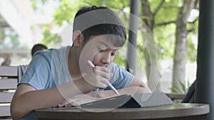 Cute asian boy using tablet computer ,Young teenage boy doing homework on digital tablet with silently face .