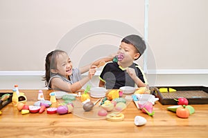 Cute Asian brother and sister having fun playing together with cooking toys at home