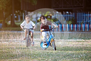 Asian child boy and his old sister having fun to ride a bicycle together in the park