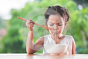 Cute asian child girl eating delicious instant noodles