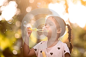 Cute asian child girl having fun to blow soap bubbles in outdoor